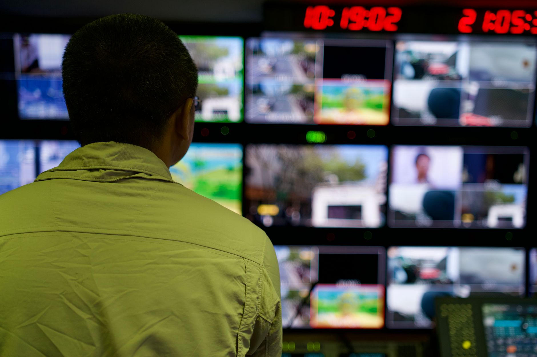 An operator monitoring a wall of screens in a control room