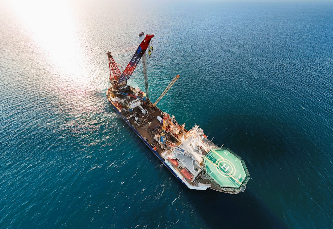 Offshore crane vessel with its boom raised, seen from the air in open water