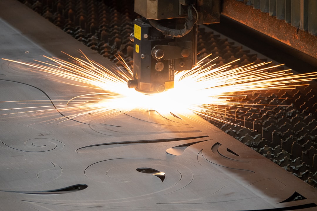 Cutting head slicing a steel plate, throwing sparks across the cutting table