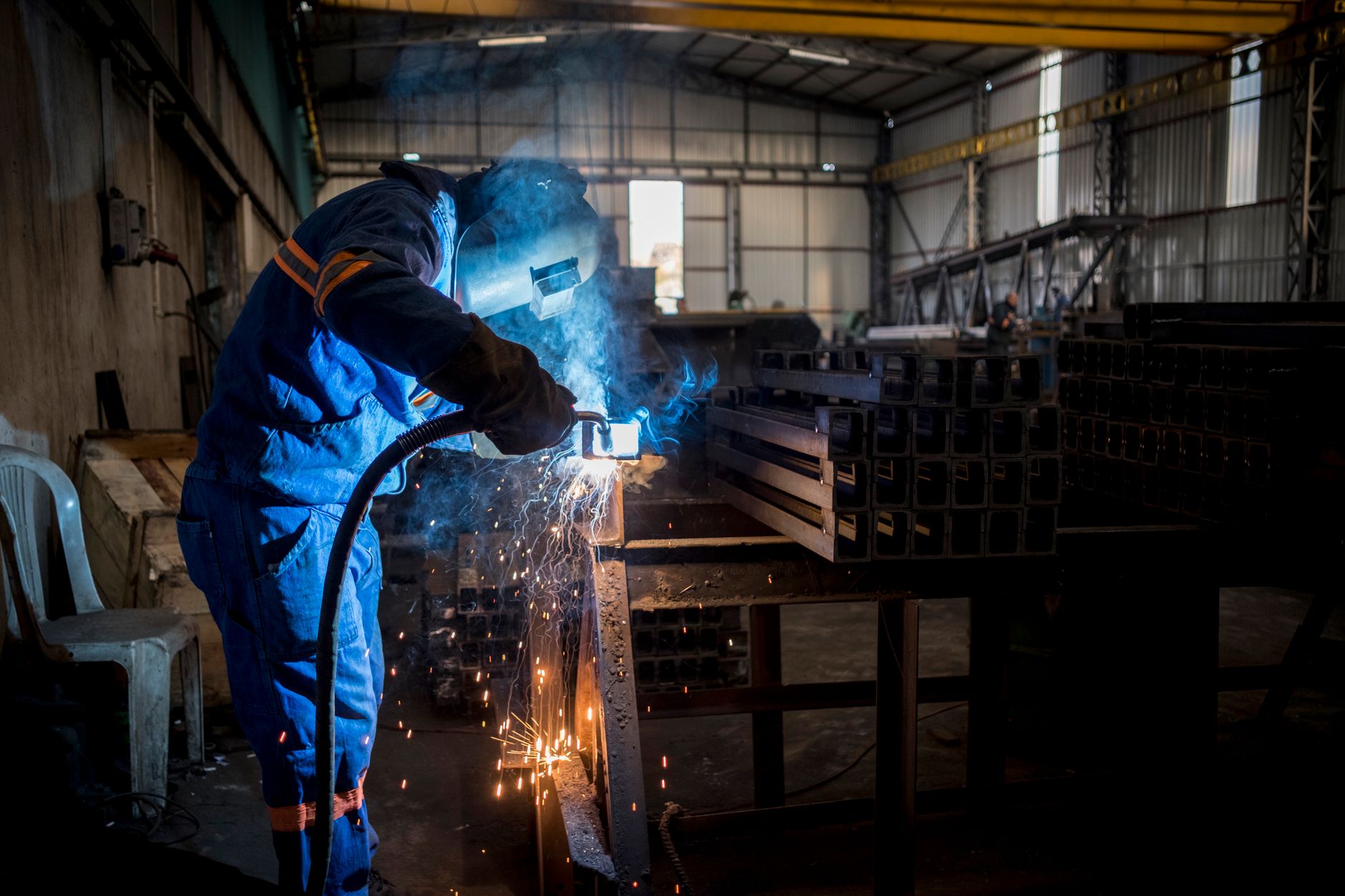 Welder joining steel sections in a heavy fabrication shop