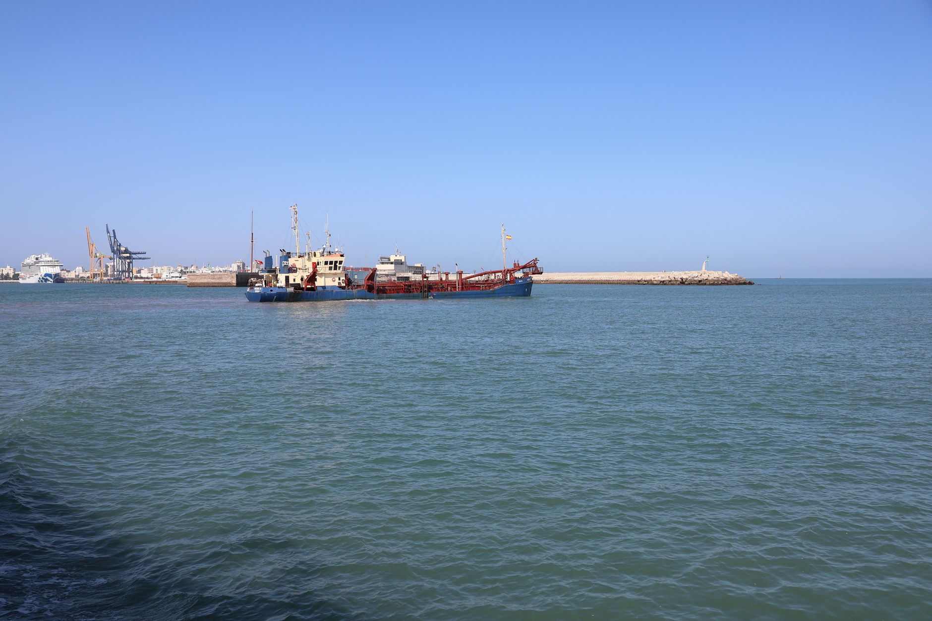 Dredger working near a port breakwater to maintain channel depth
