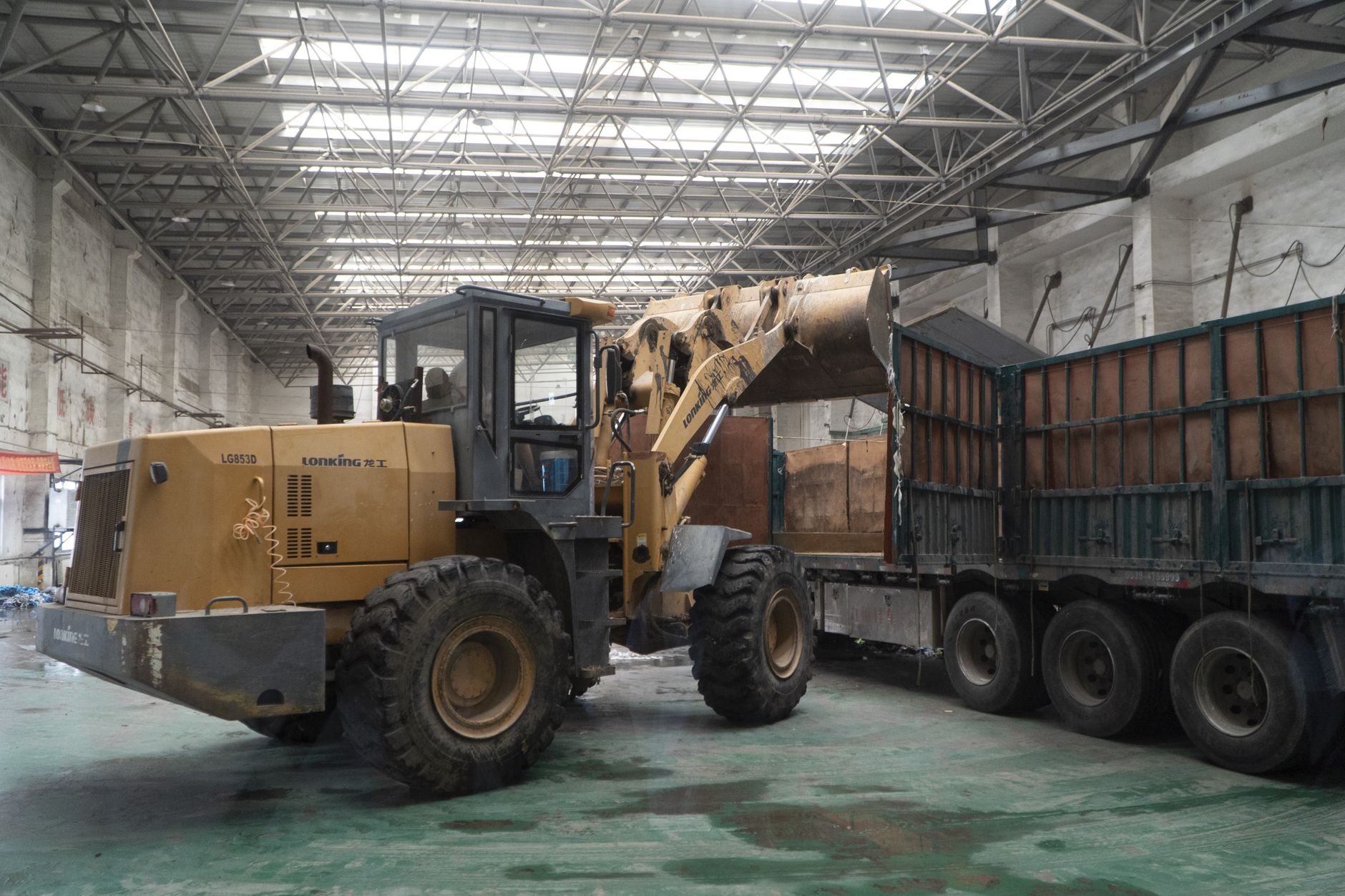A wheel loader transferring cargo into a truck inside a warehouse