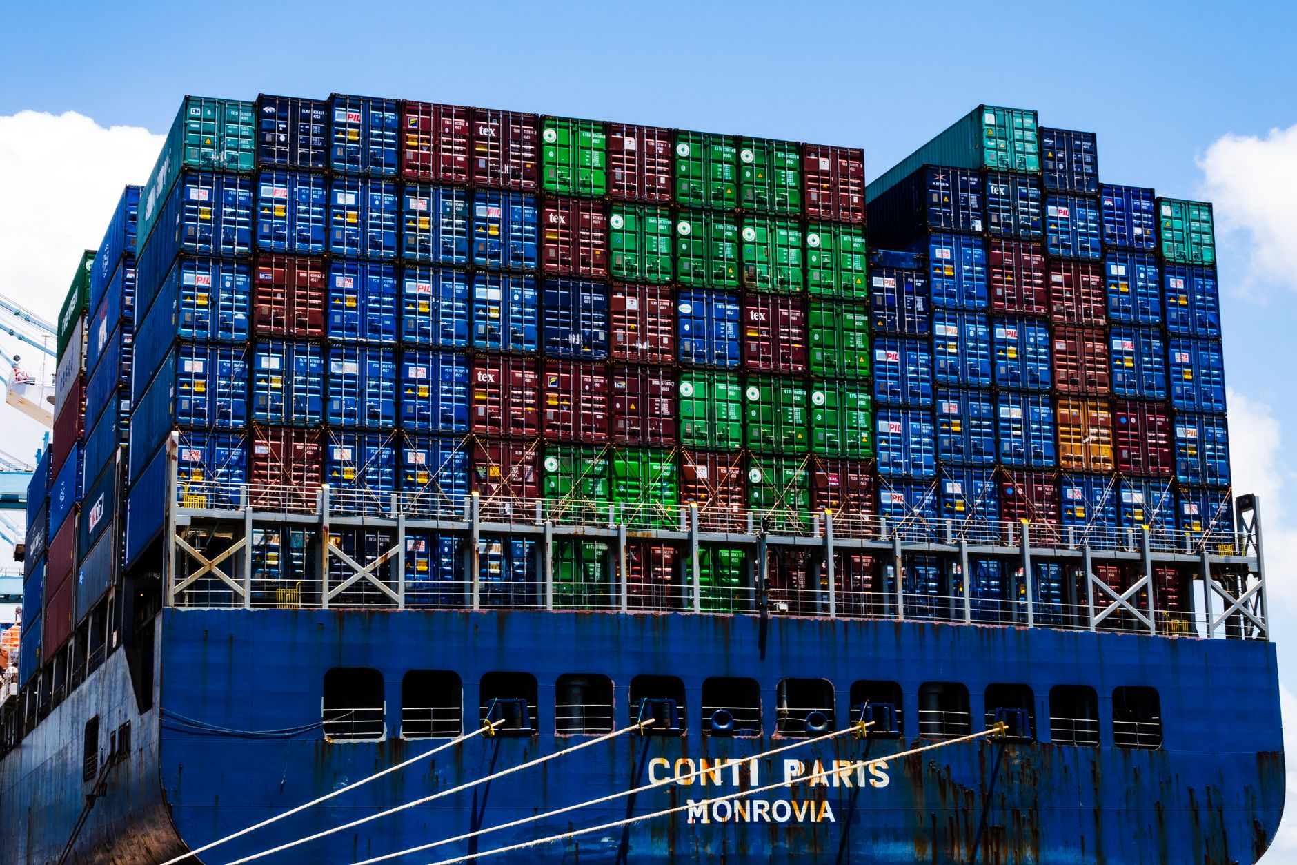A container ship loaded high with mixed containers lying alongside a quay