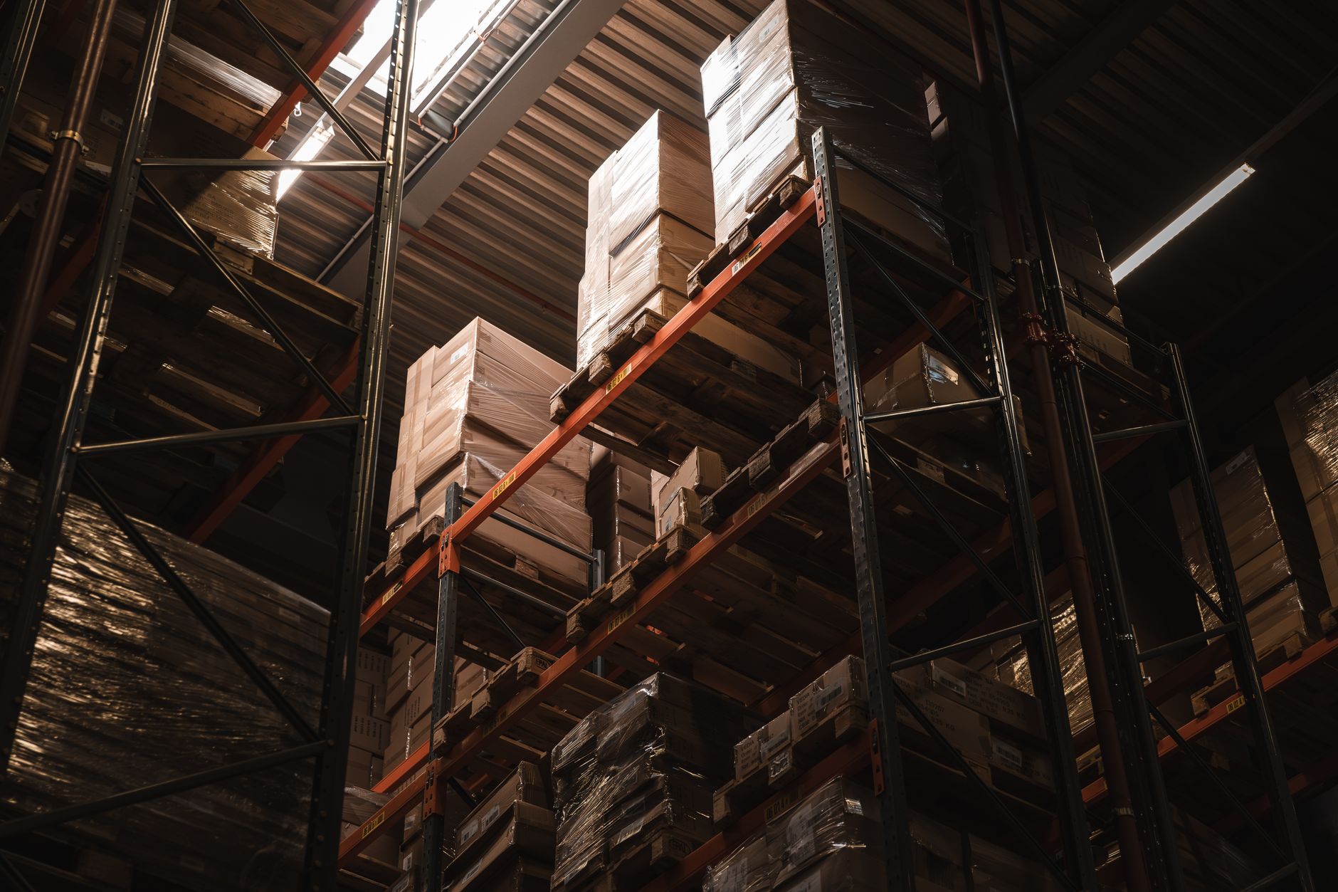 Wrapped pallets racked several levels high in a dimly lit warehouse