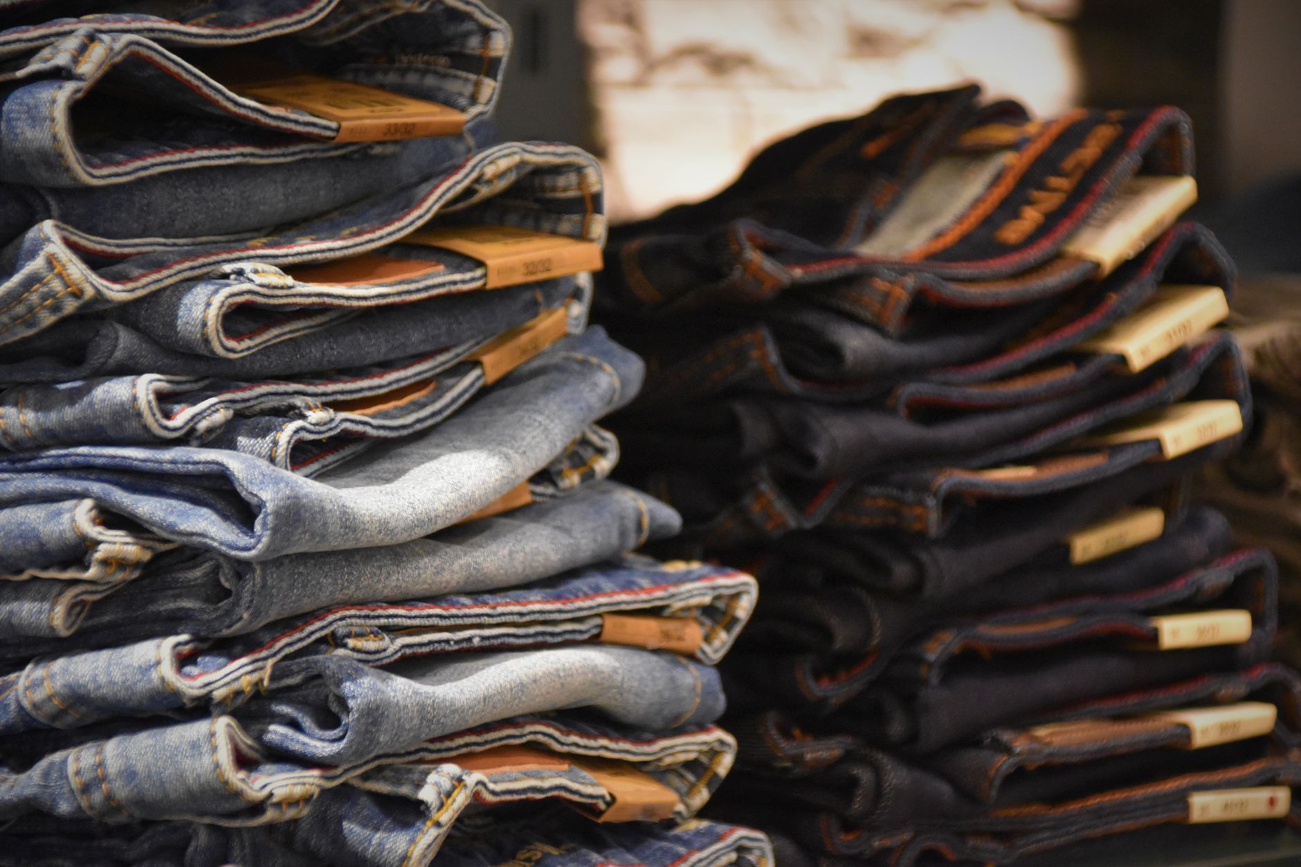 Two stacks of folded denim jeans with size tags in a retail display