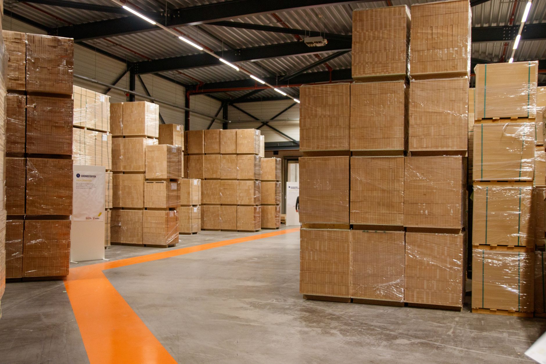 Stretch-wrapped pallets of flat-packed board stacked in a distribution hall