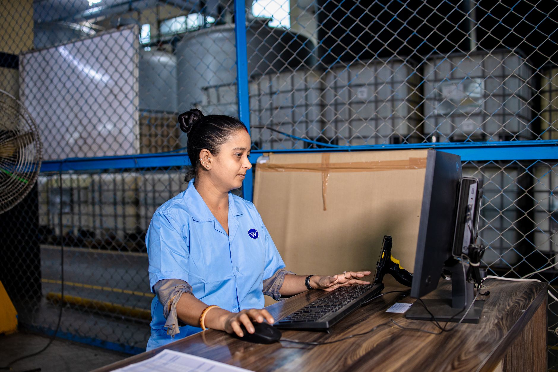 Warehouse worker entering shipment data at a computer with a barcode scanner