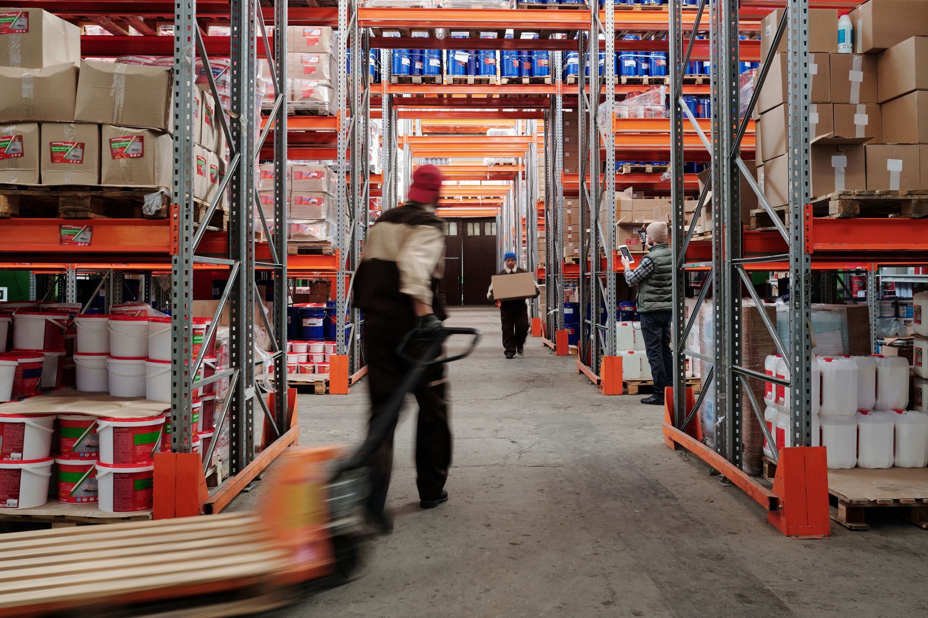 Racked pallet positions in a distribution warehouse with pallet trucks in motion
