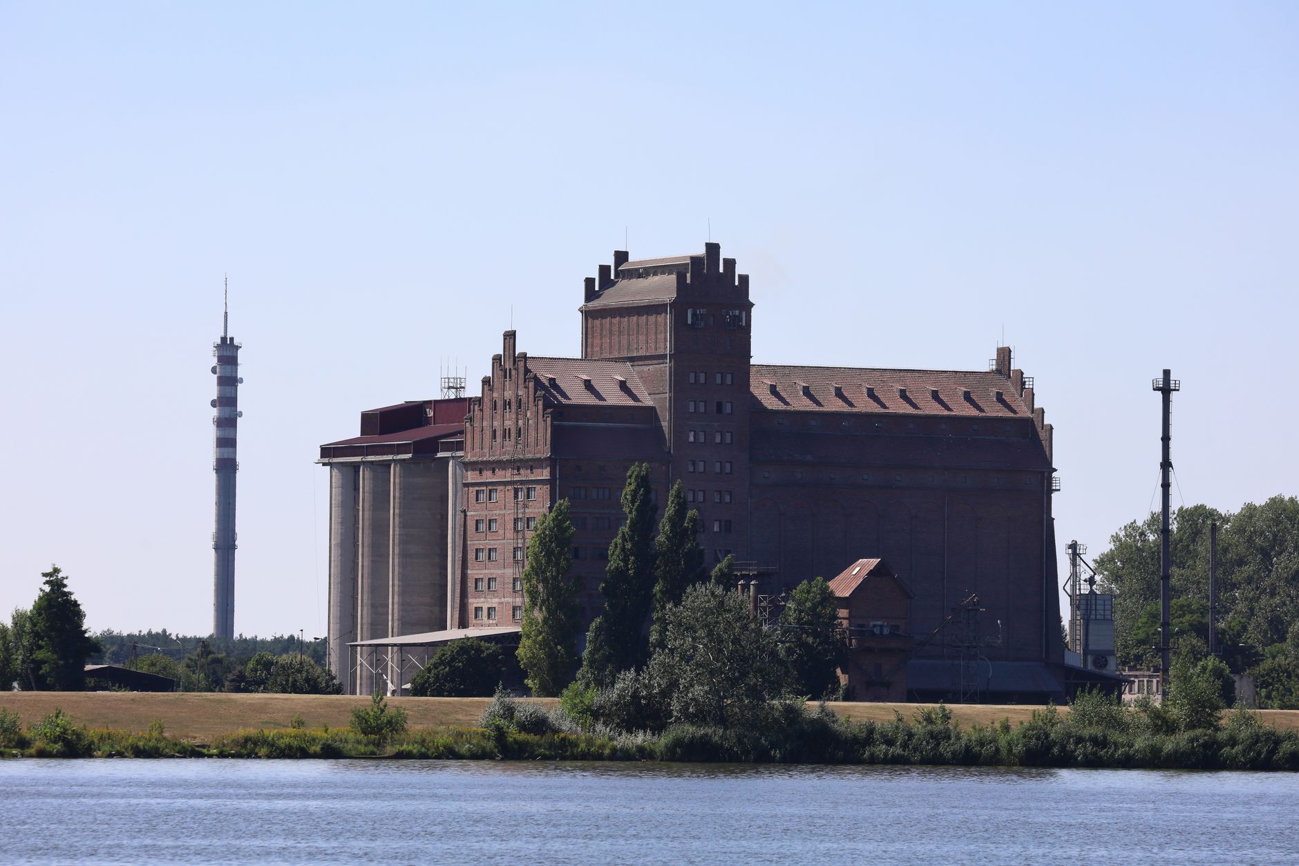 Brick grain elevator with concrete silos standing on a riverbank