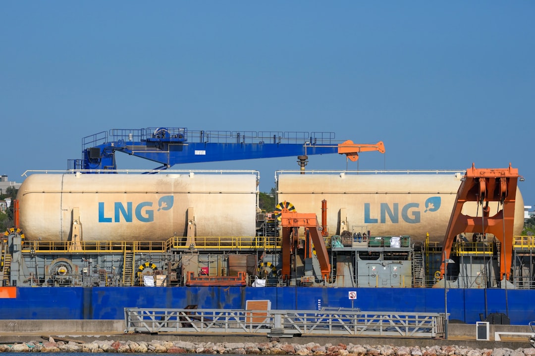 Two cryogenic LNG tanks lettered LNG with deck cranes above them