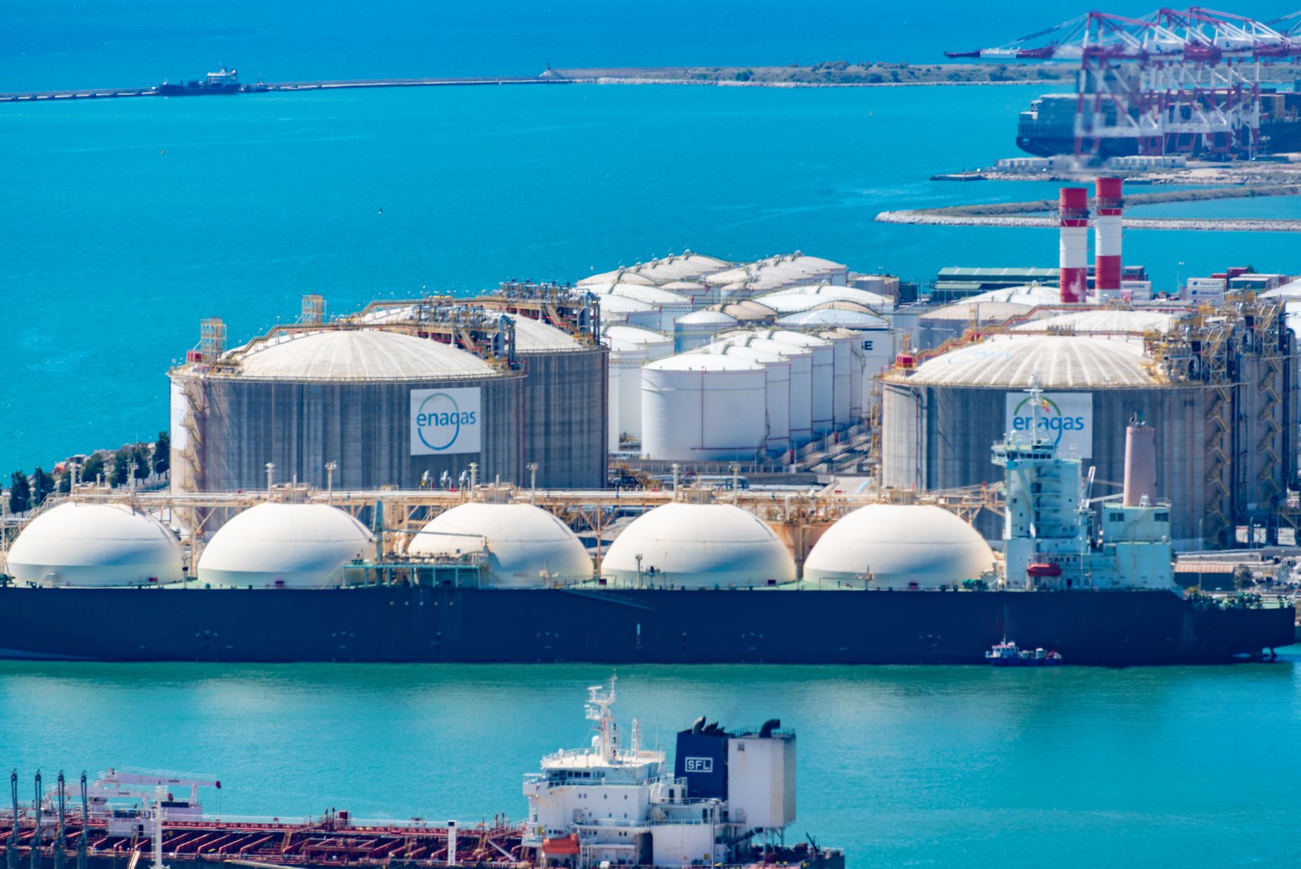 Aerial view of an LNG import terminal with storage tanks and a gas carrier alongside