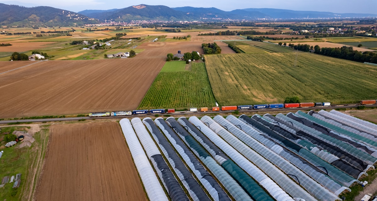 Long container freight train crossing farmland in a river valley