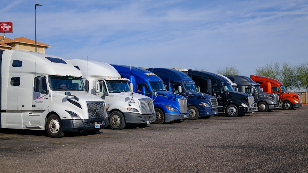 Row of new heavy trucks parked at a manufacturing plant