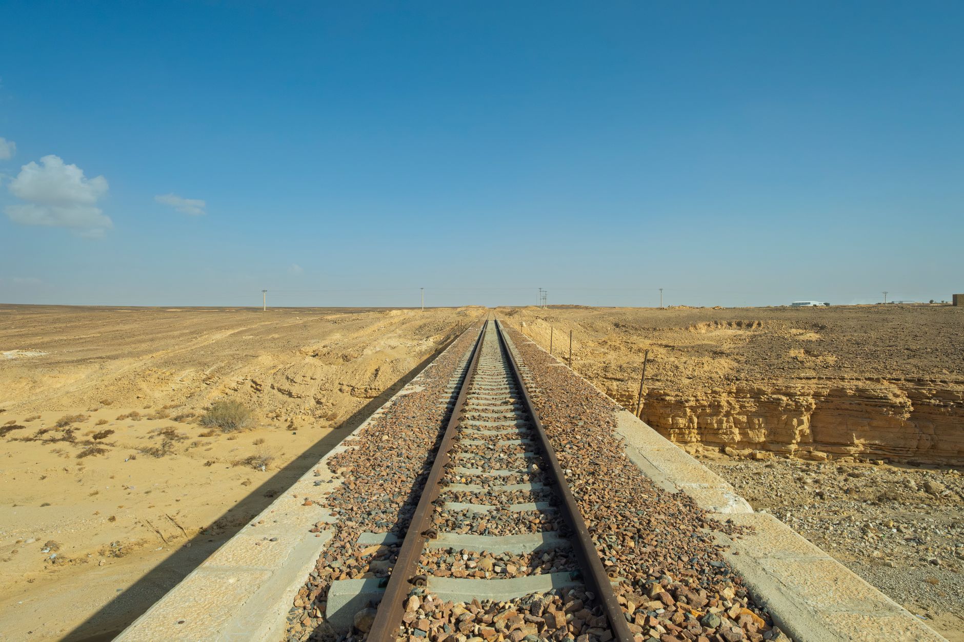 A single-track railway line running straight through arid terrain