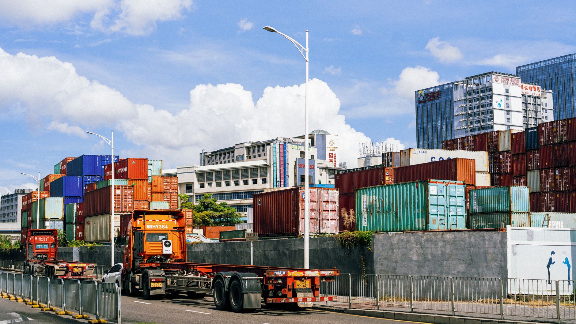 Truck hauling a container past stacked boxes