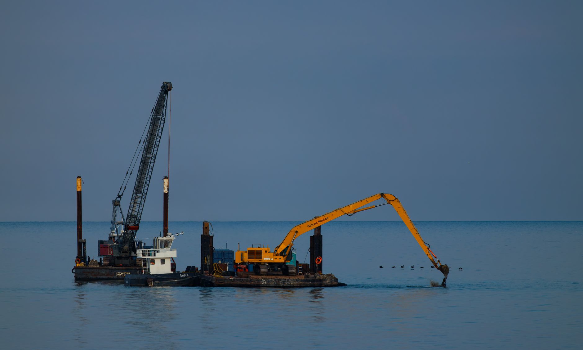 Floating dredging platform with an excavator arm on open water