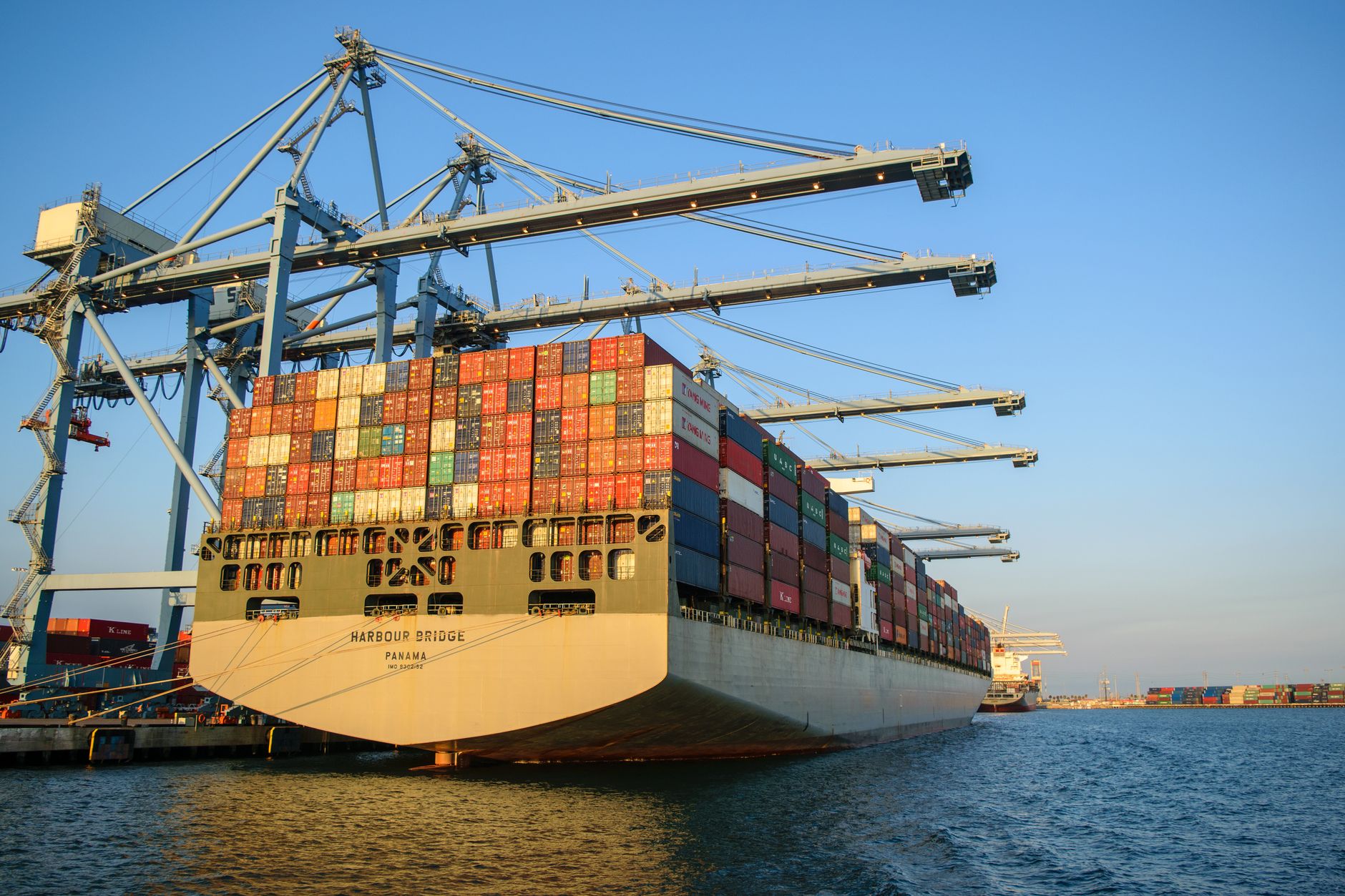 A loaded container ship berthed under gantry cranes