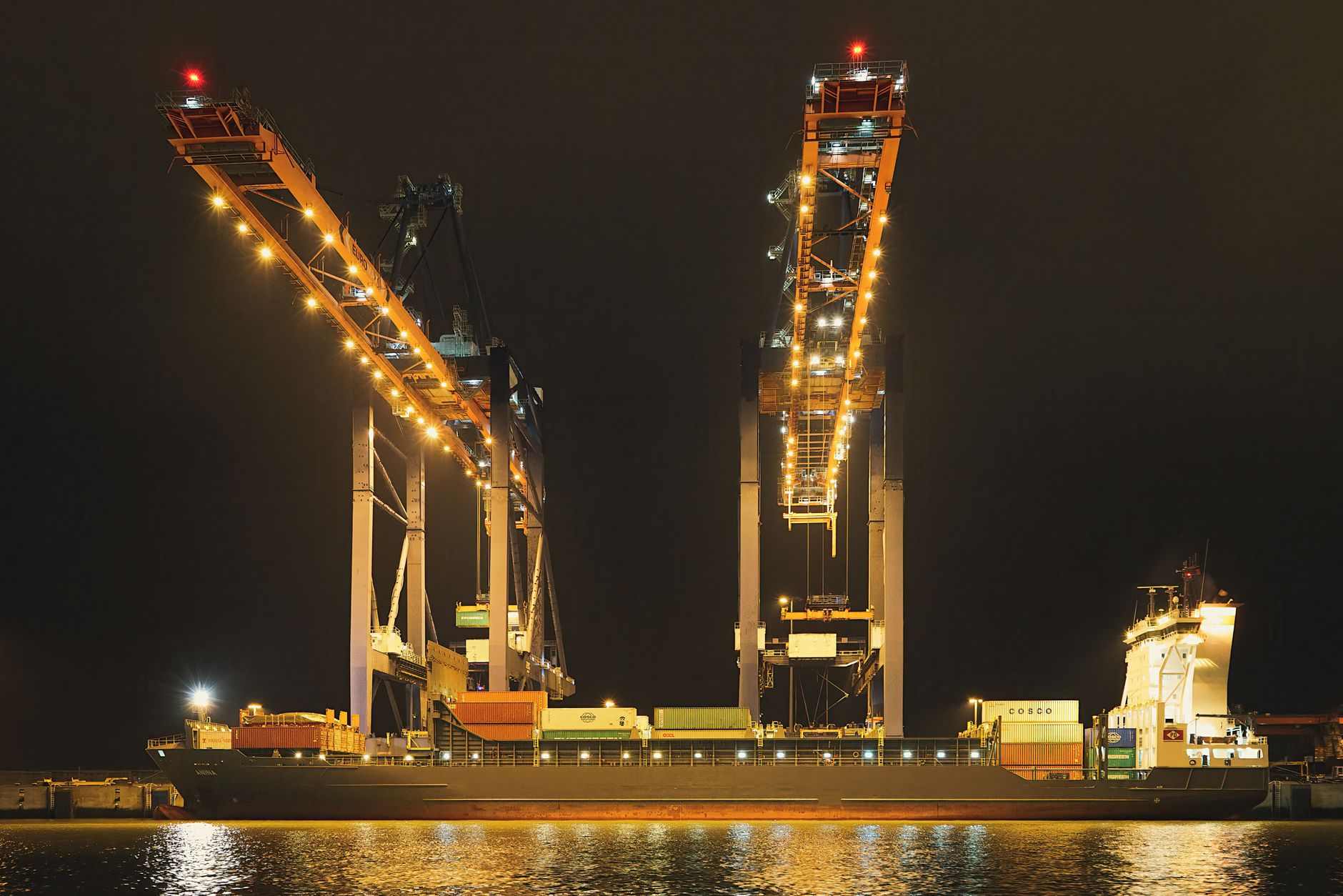Container ship at a night terminal under quay cranes