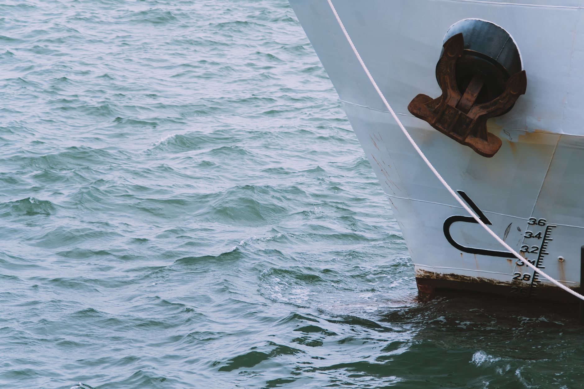 The bow of a loaded ship showing draft marks as it cuts through open water